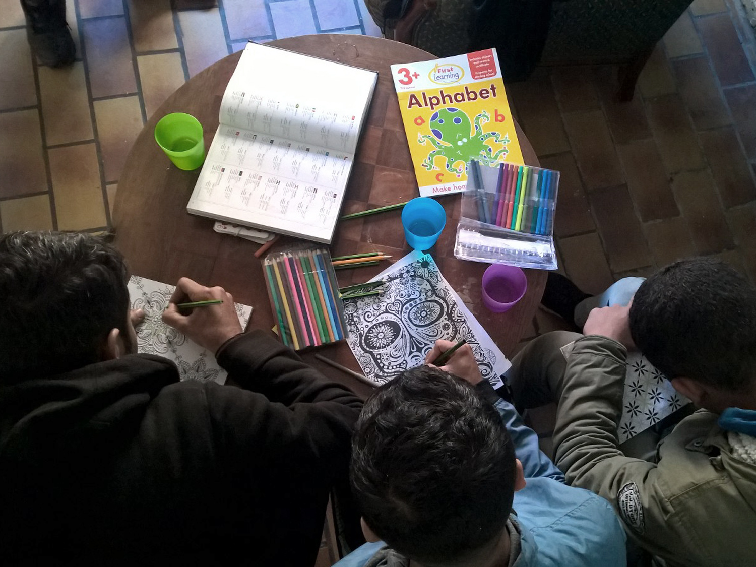 Children colouring in with alphabet textbook