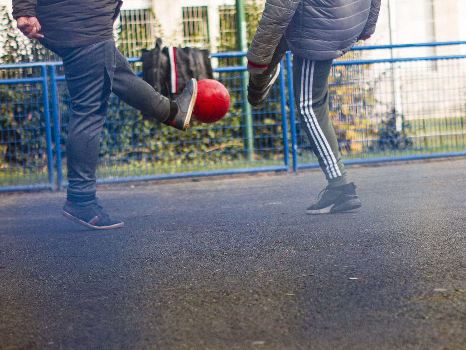 Two boys kicking a football in a playground